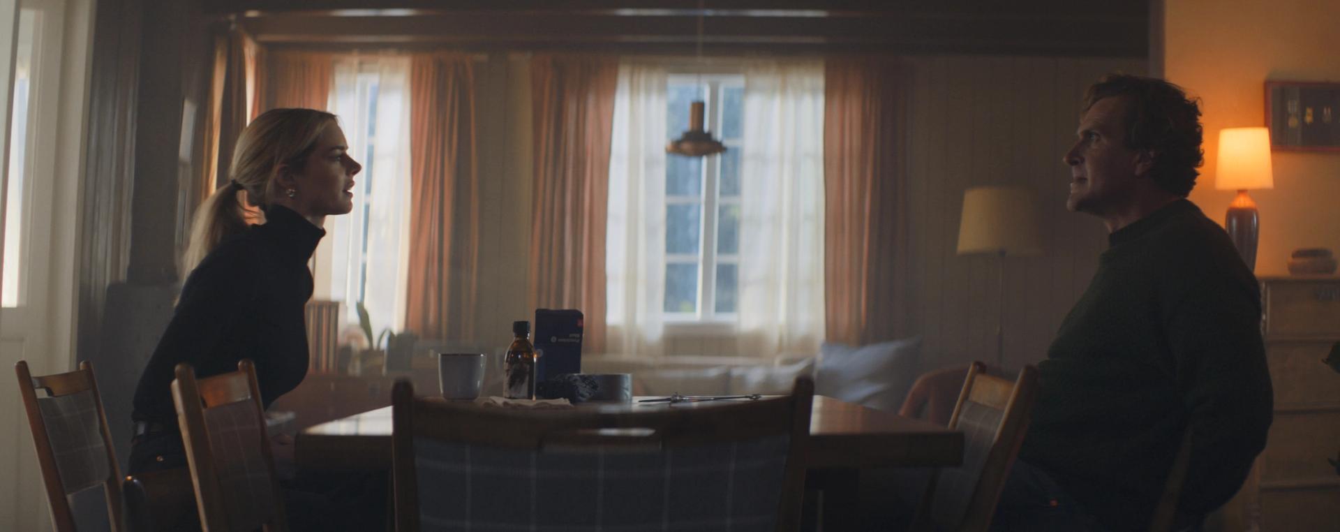 Samara Weaving and Jason Segel sitting at a wooden table.