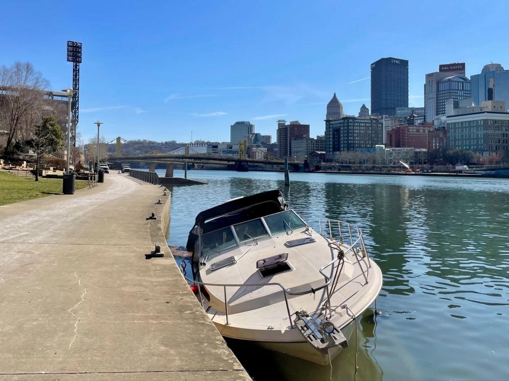 a boat retaining river water is tied up next to a baseball stadium