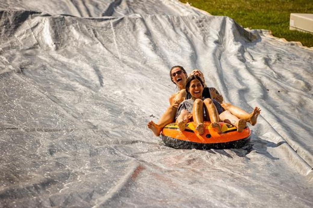 Two people in an inner tube sliding down a hill. 