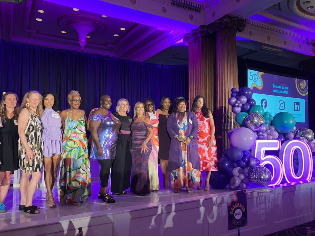 A group of women post for a photo on stage