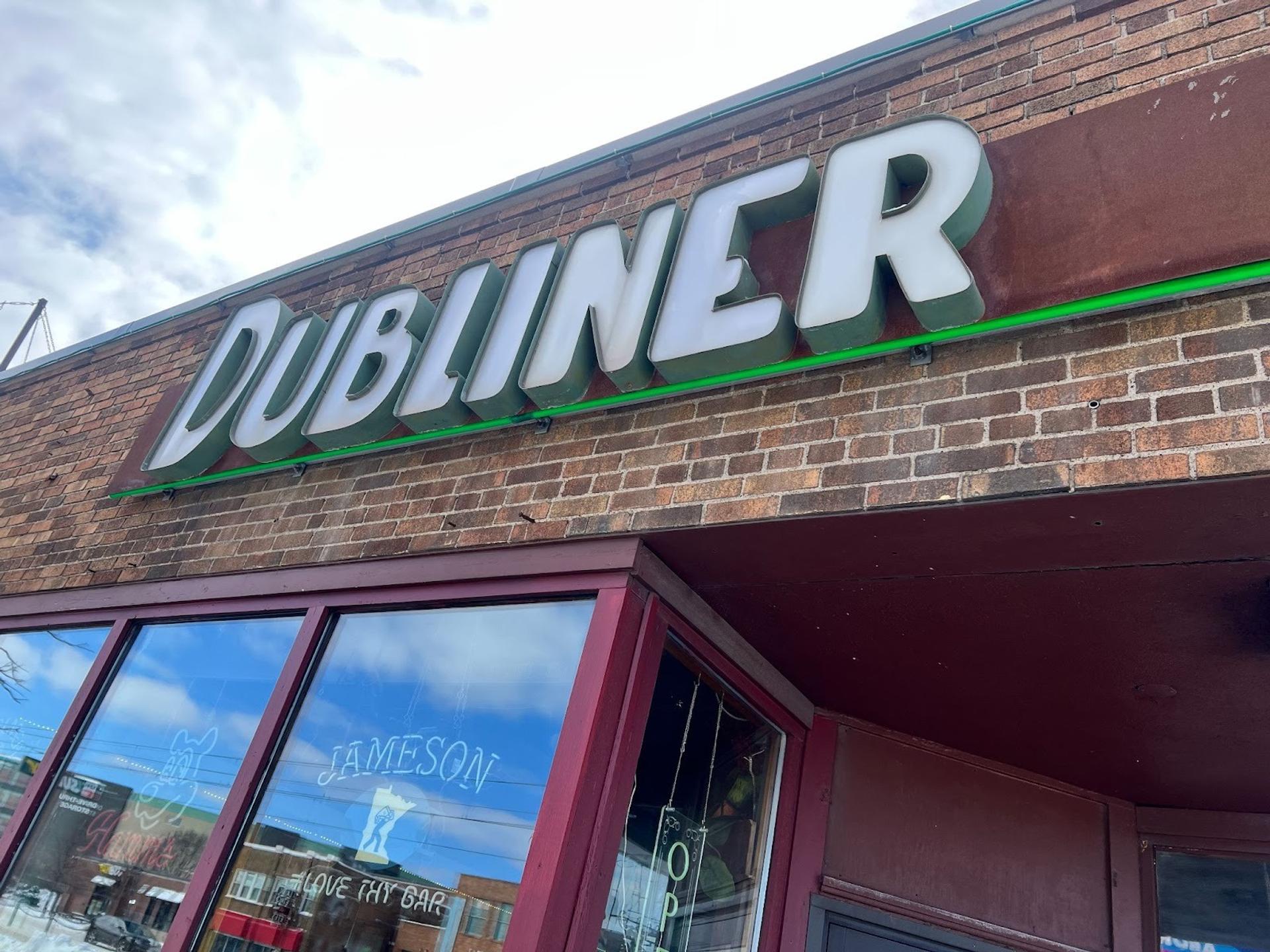 A brick building with a large light up sign that says "Dubliner"