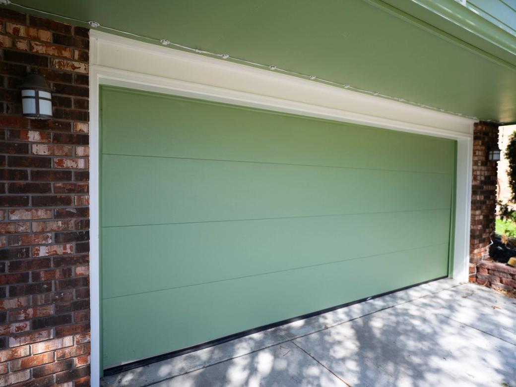 Exterior view of closed light green garage door on brick house