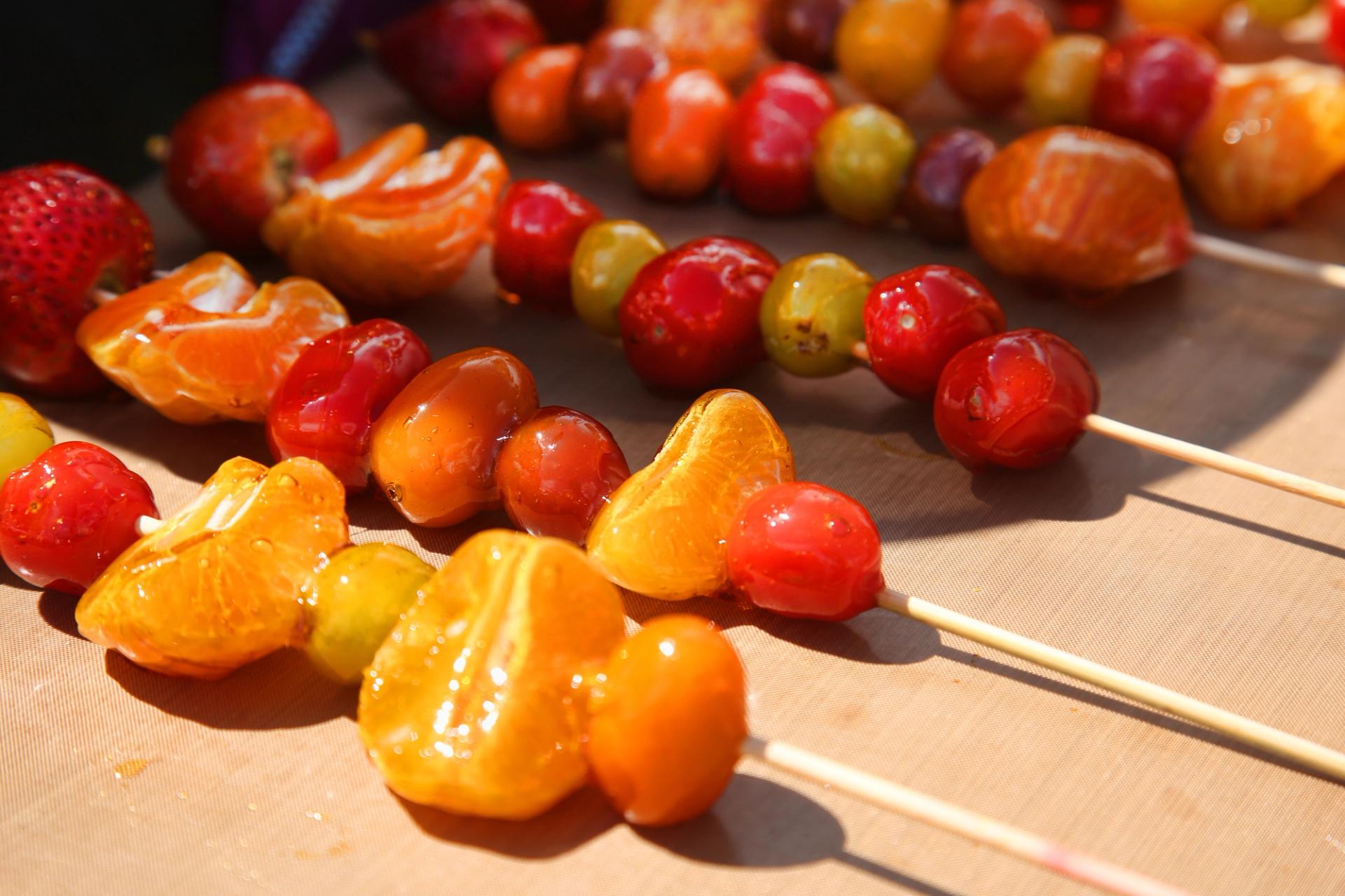 Tanghulu candied fruit skewers on a market table
