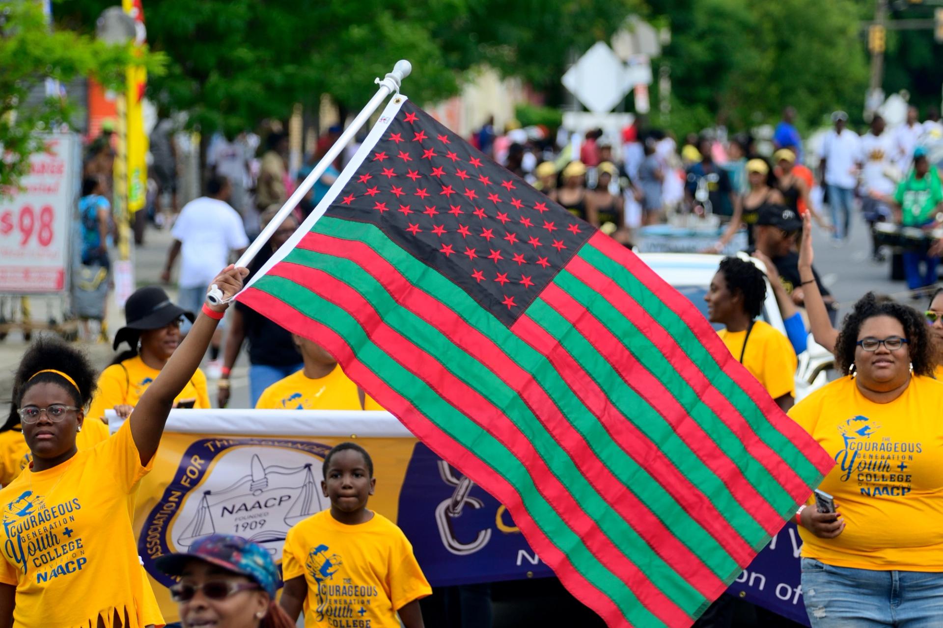 A person waving a flag at the 2019 Juneteenth Parade in Philly.