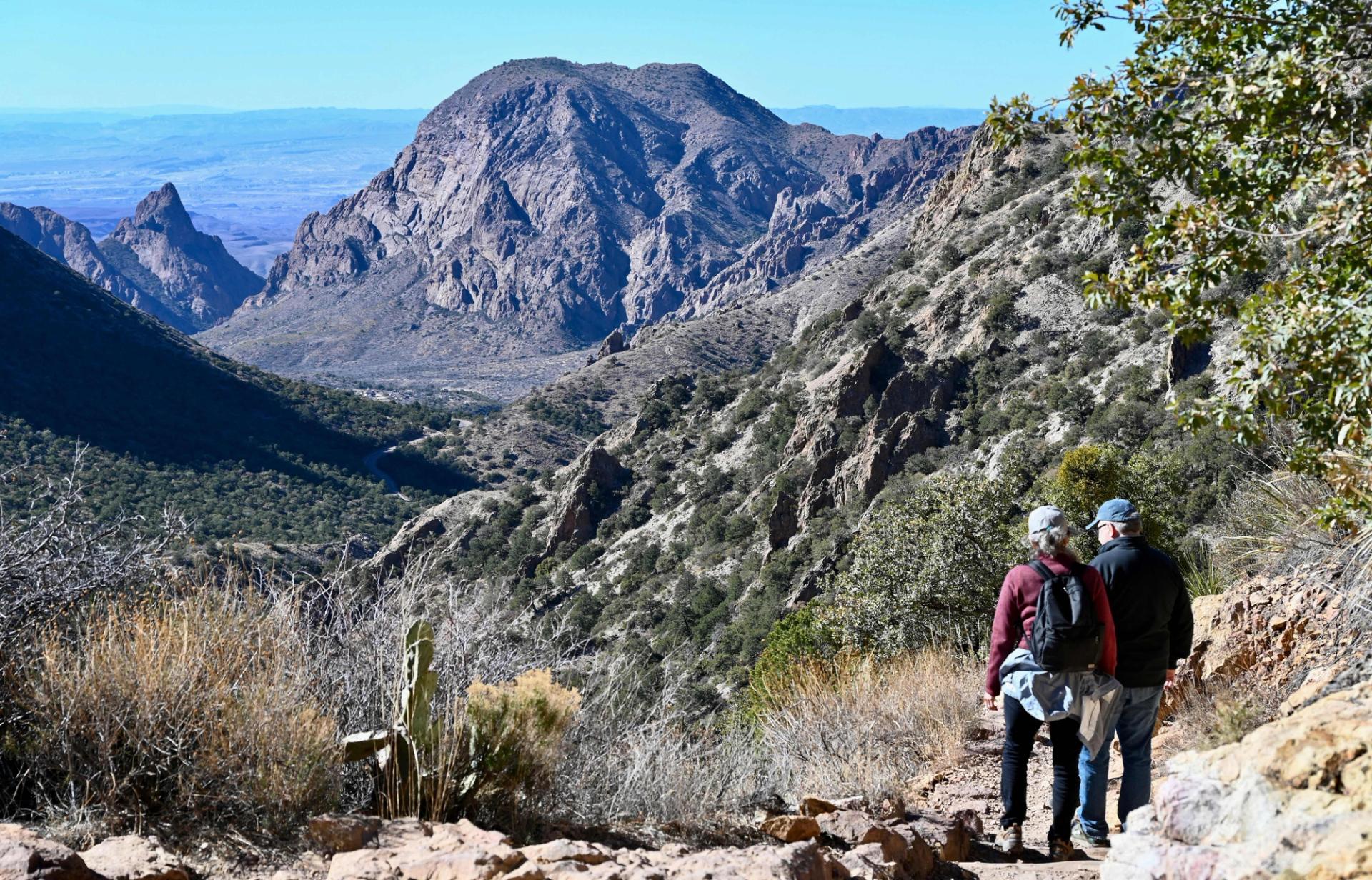 Two campers wearing backpacks lookout at Big Bend National Park.