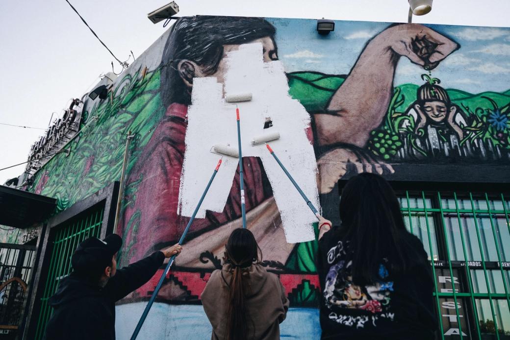 Local artists paint over a mural of César Chávez in Westwood