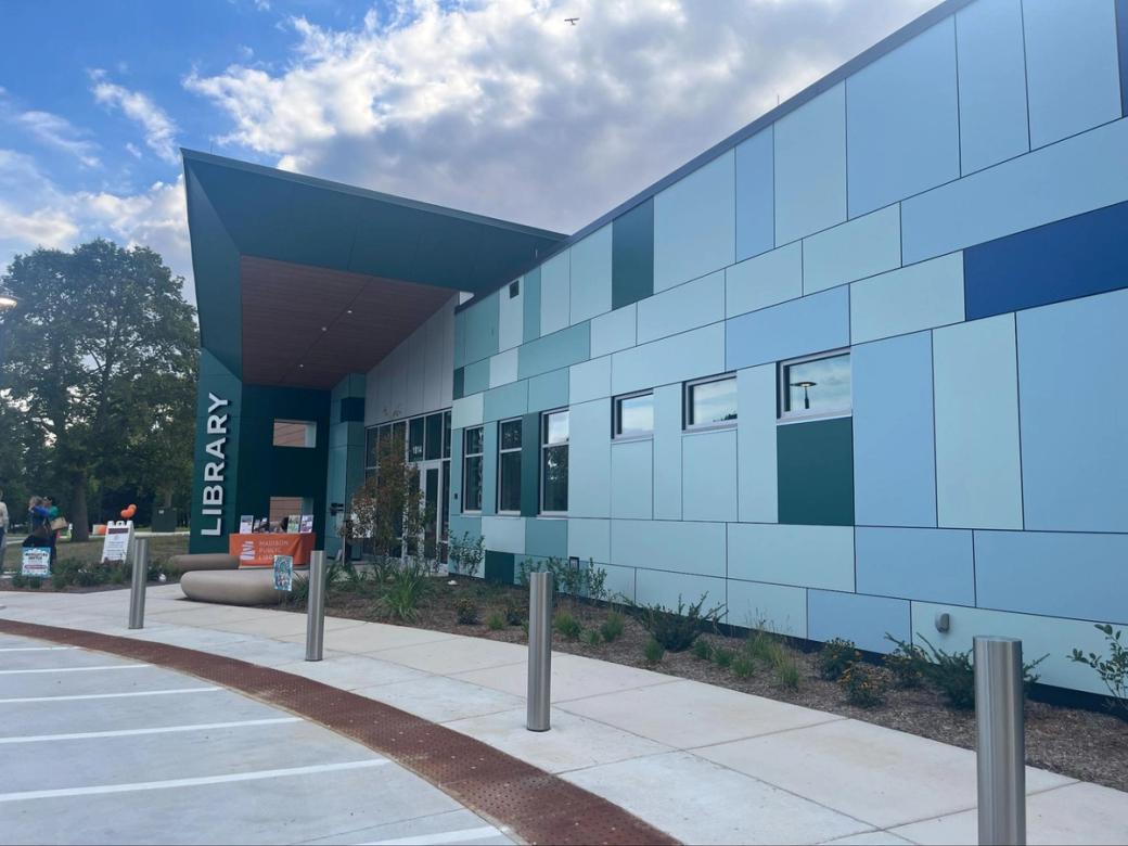 The outside of the Imagination Center with blue tiles and a vertical sign that reads "Library."