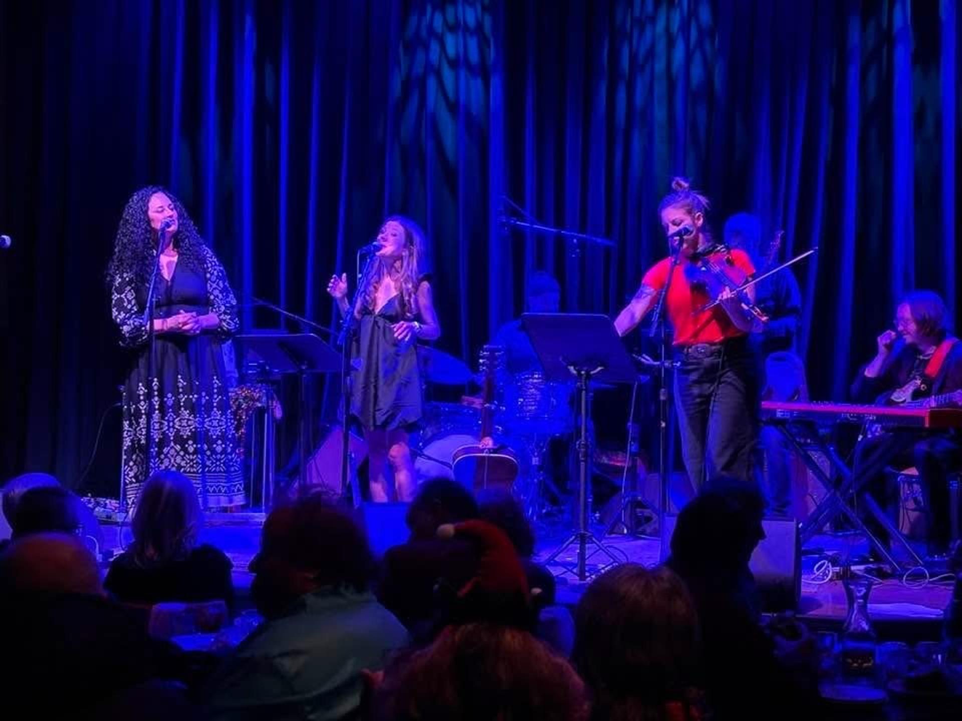 A group of people on stage playing instruments and singing