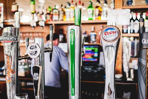 Multiple beers on tap included Lamps, Heineken, Coors Light, and Guinness at a bar.
