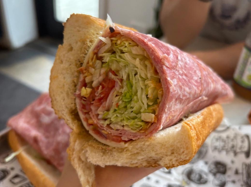 A hoagie stuffed with meats, lettuce, tomato, and cheese.