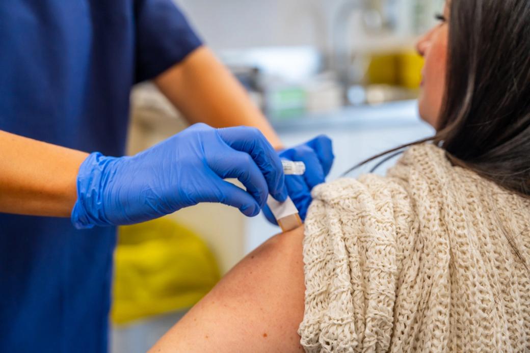 Nurse applying a bandaid to a person’s arm after a flu shot.
