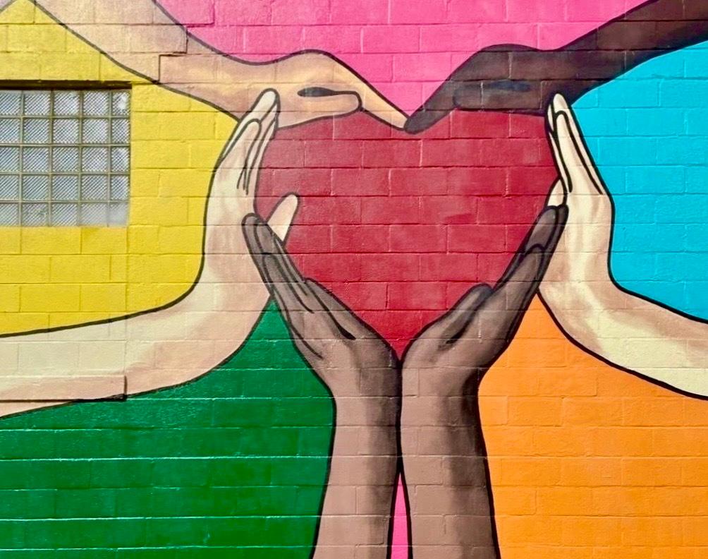 a mural of a red heart held by hands of different races