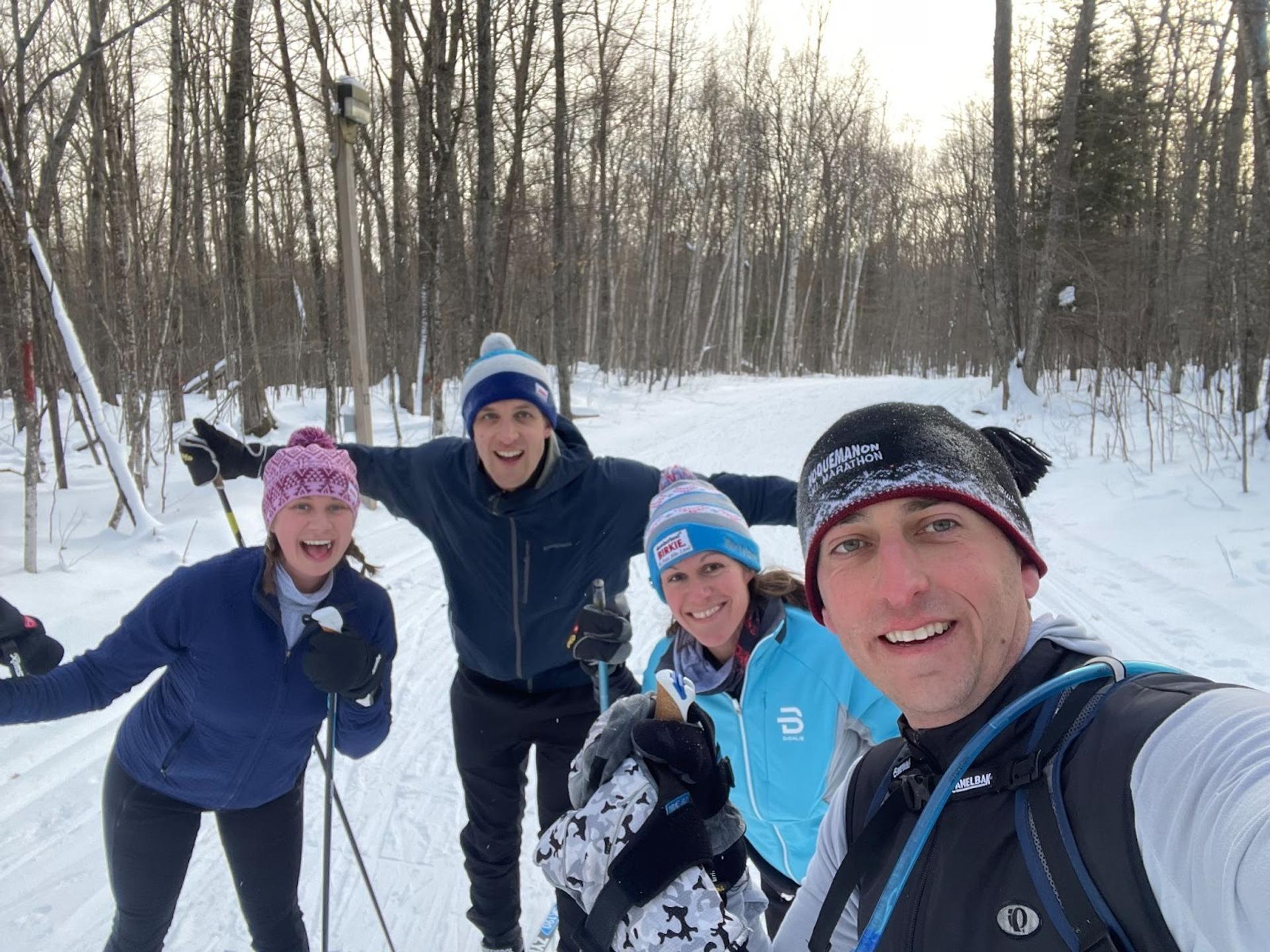 A selfie of four people warmly dressed in the snow