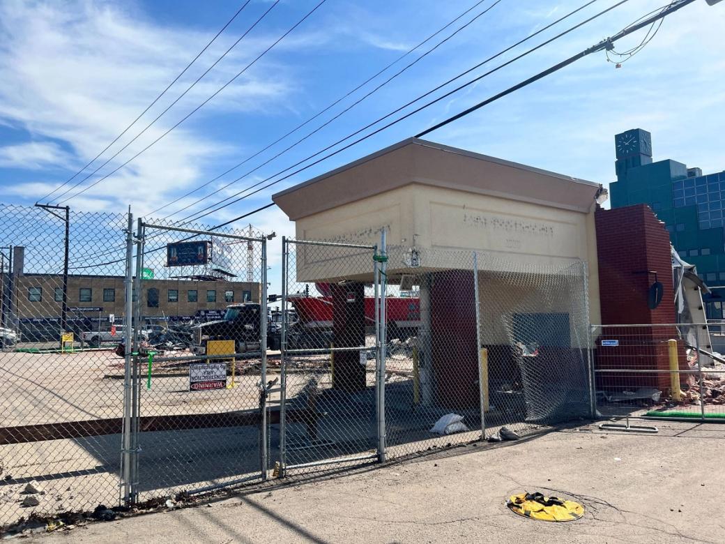 Partly demolished building surrounded by chain-link fence