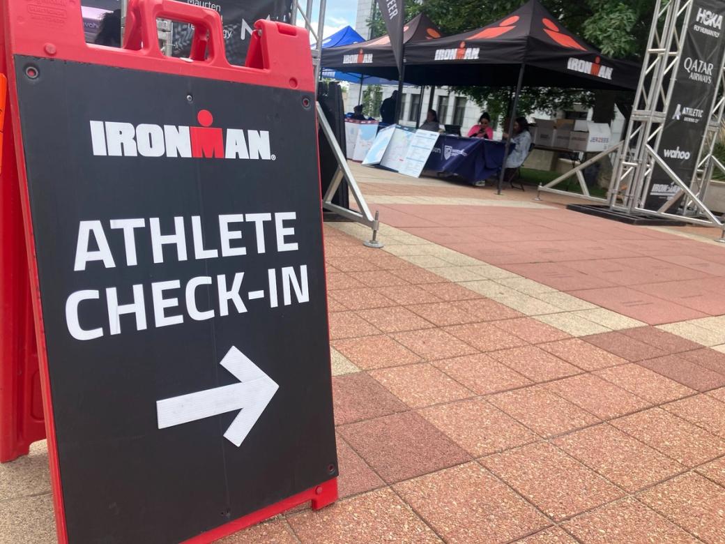 A red Ironman sign has an arrow pointing to the right and reads "Athlete Check-In."