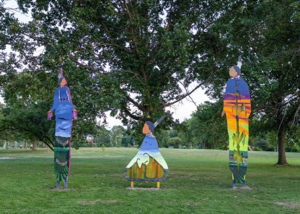 Three colorful art installations stand in a park.