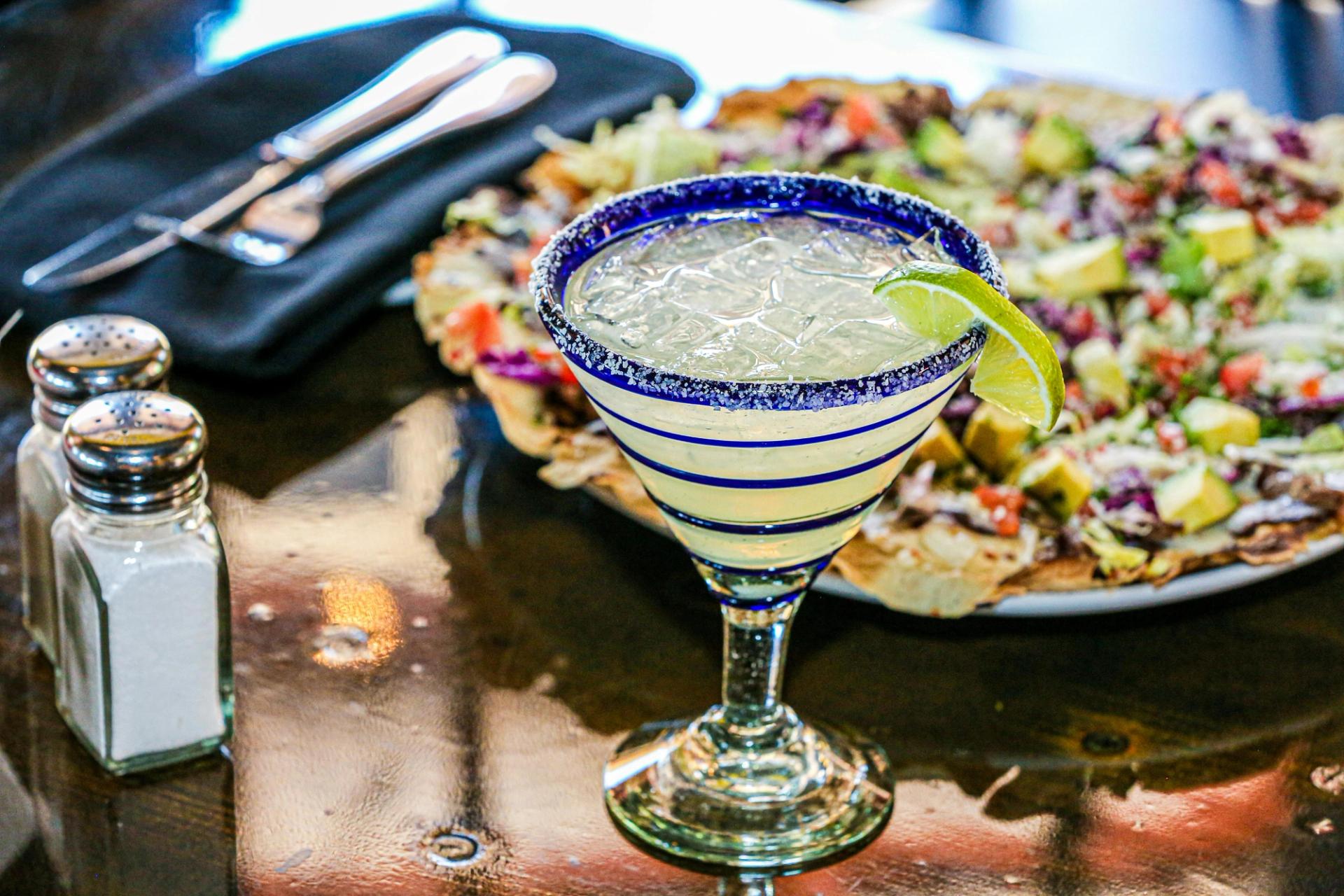 A margarita with a plate of Mexican food.