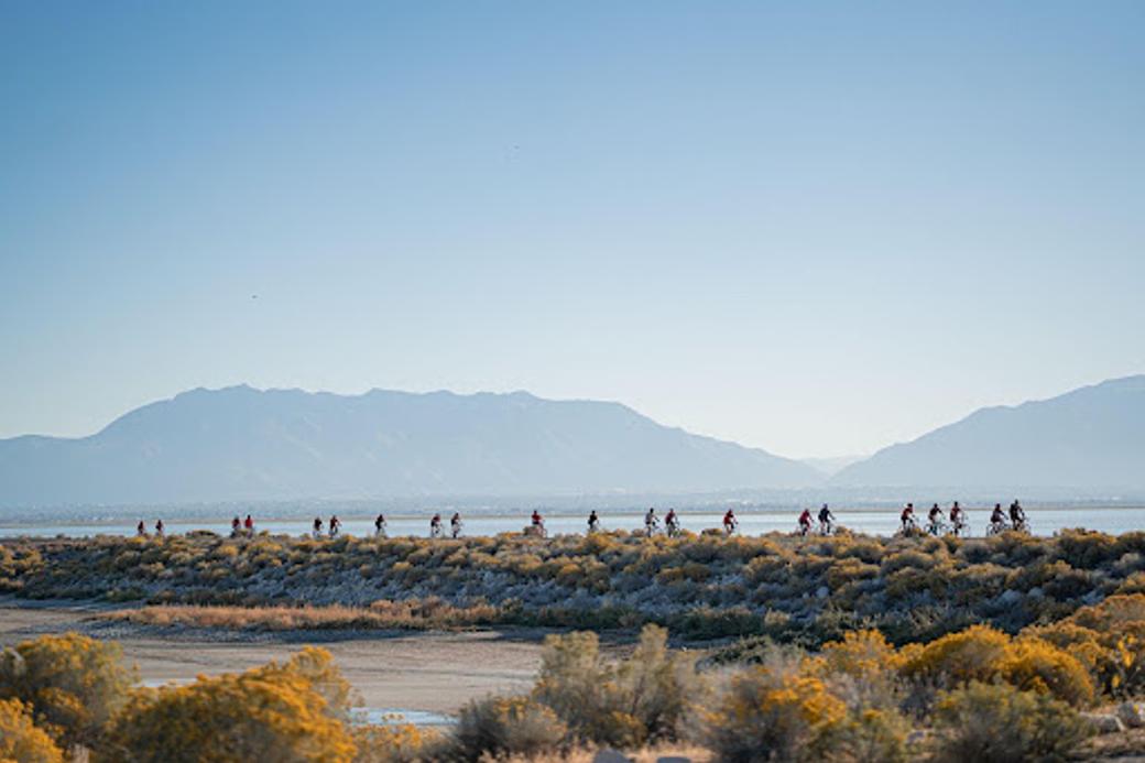 People dressed in red ride bikes across the Great Salt Lake causeway to Antelope Island.