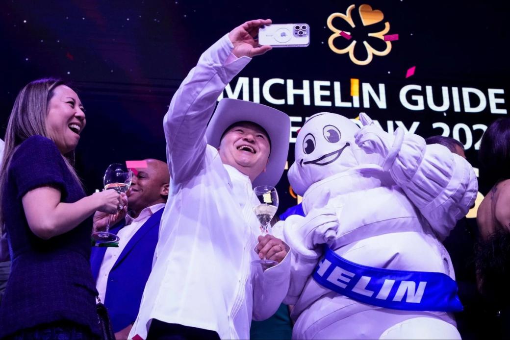 A man taking a selfie with the Michelin mascot.