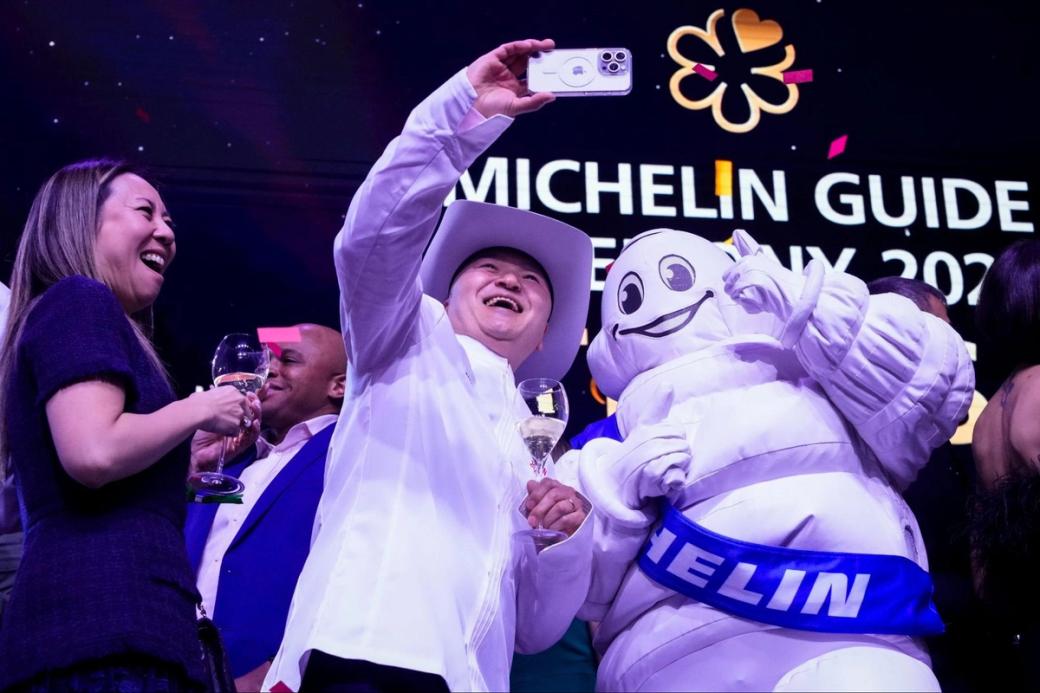 A man taking a selfie with the Michelin mascot.