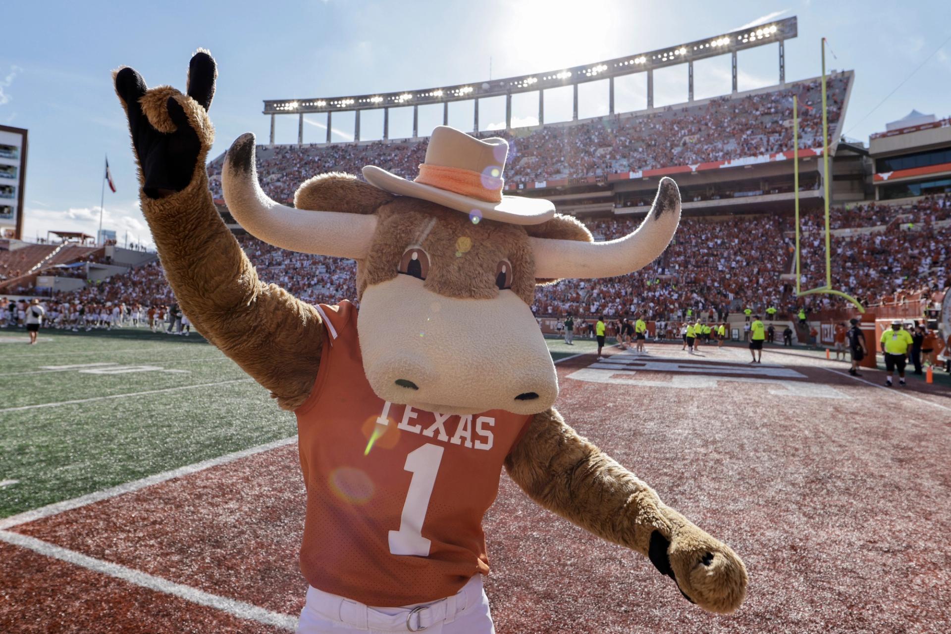 The University of Texas at Austin mascot Bevo throwing a "horns up" inside the football stadium.