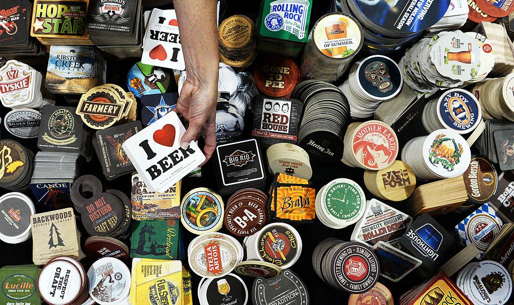 An overhead shot of hundreds of coasters displaying brewery logos