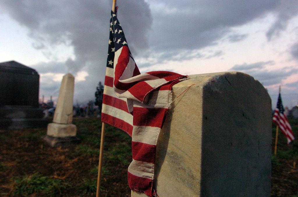 An American flag clings to a headstone at Denver’s Riverside cemetery.