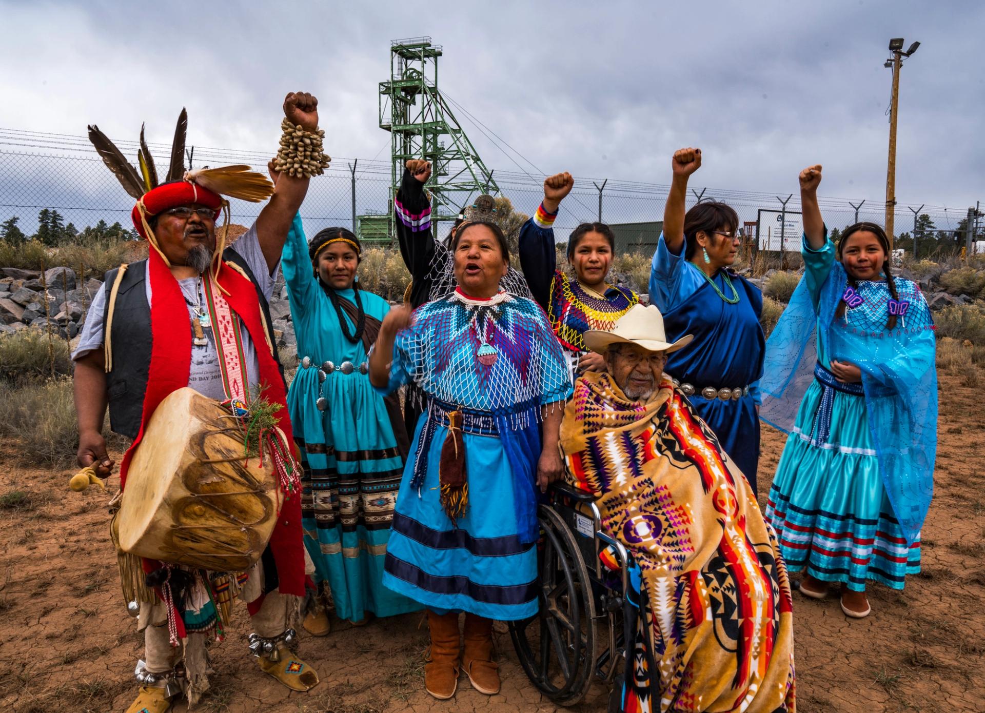 A group of people in brightly colored garb raising their fists.