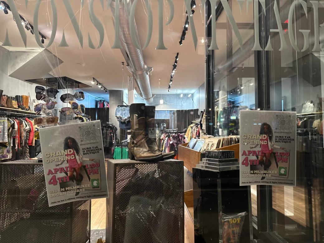 Retail clothing establishment, as viewed from the exterior of front window which has "Grand Opening" posters