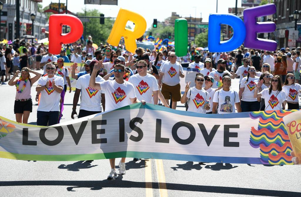 People holding a "Love is Love" banner march in the 2023 Denver Pride Parade.