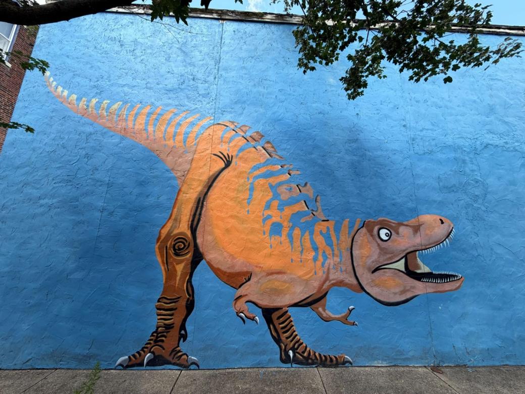 A tyrannosaurus rex mural on a blue wall.