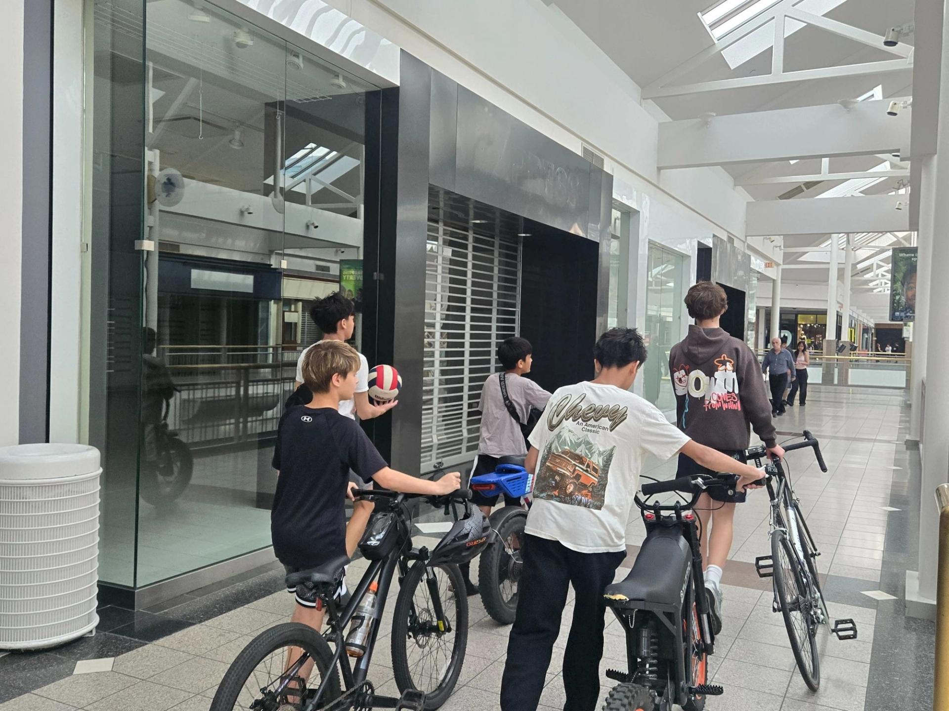 A group of preteens walking their bikes in the mall