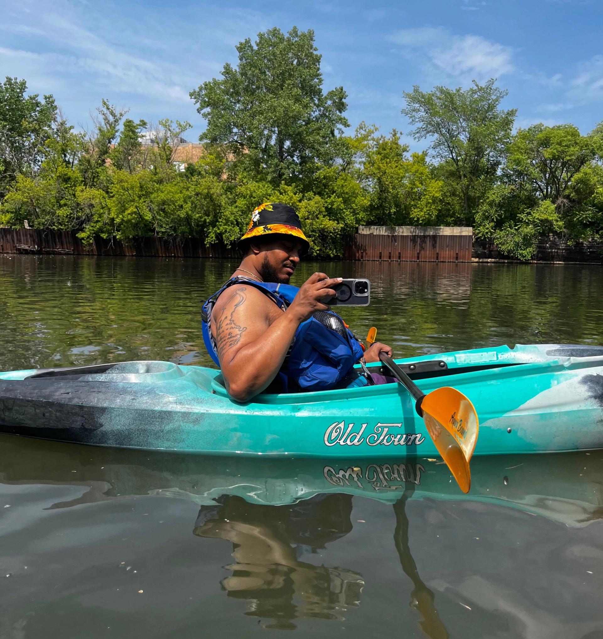 Jacoby in a kayak takes a photo on his phone