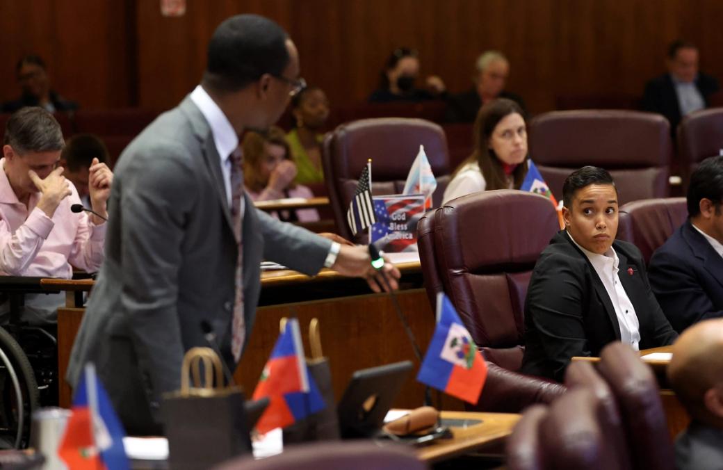 A man standing in a court while another person across the aisle looks at him