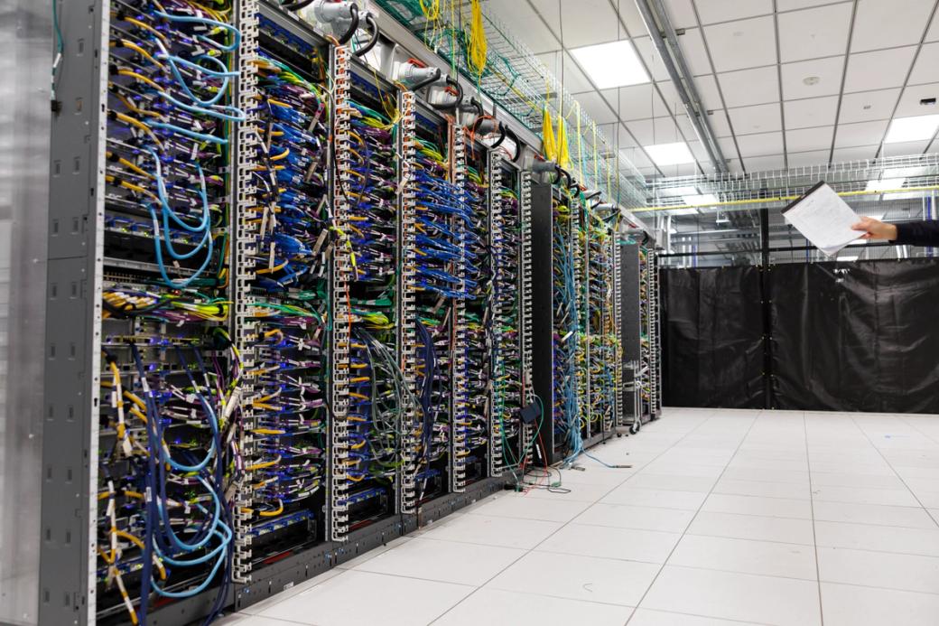 Room filled with data servers, lit by fluorescent lighting from dropped ceilings overhead