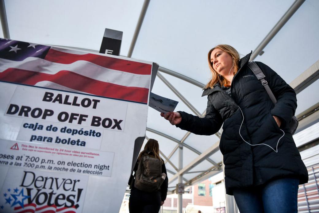 A voter drops off a ballot at a Denver ballot drop box