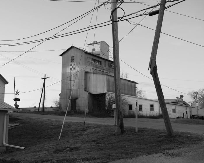 A two-story wooden building sits by the side of the road. 