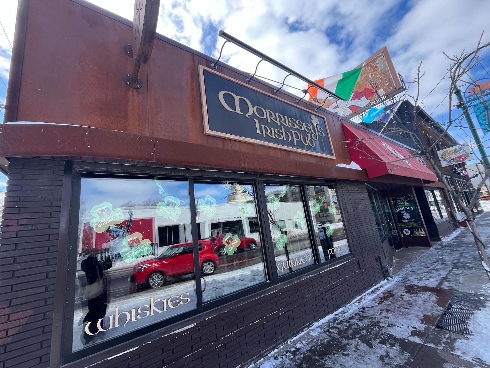 A brick building. There are reflective windows and clover decorations. The sign on the building says "Morrissey's Irish Pub"