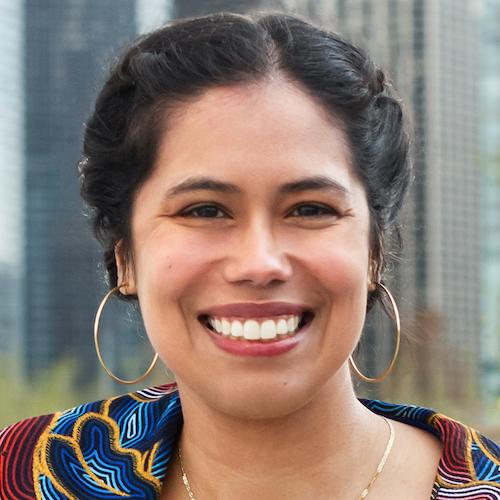 photo of a woman with braided up-do, large gold hoop earrings, and colorful pattern top
