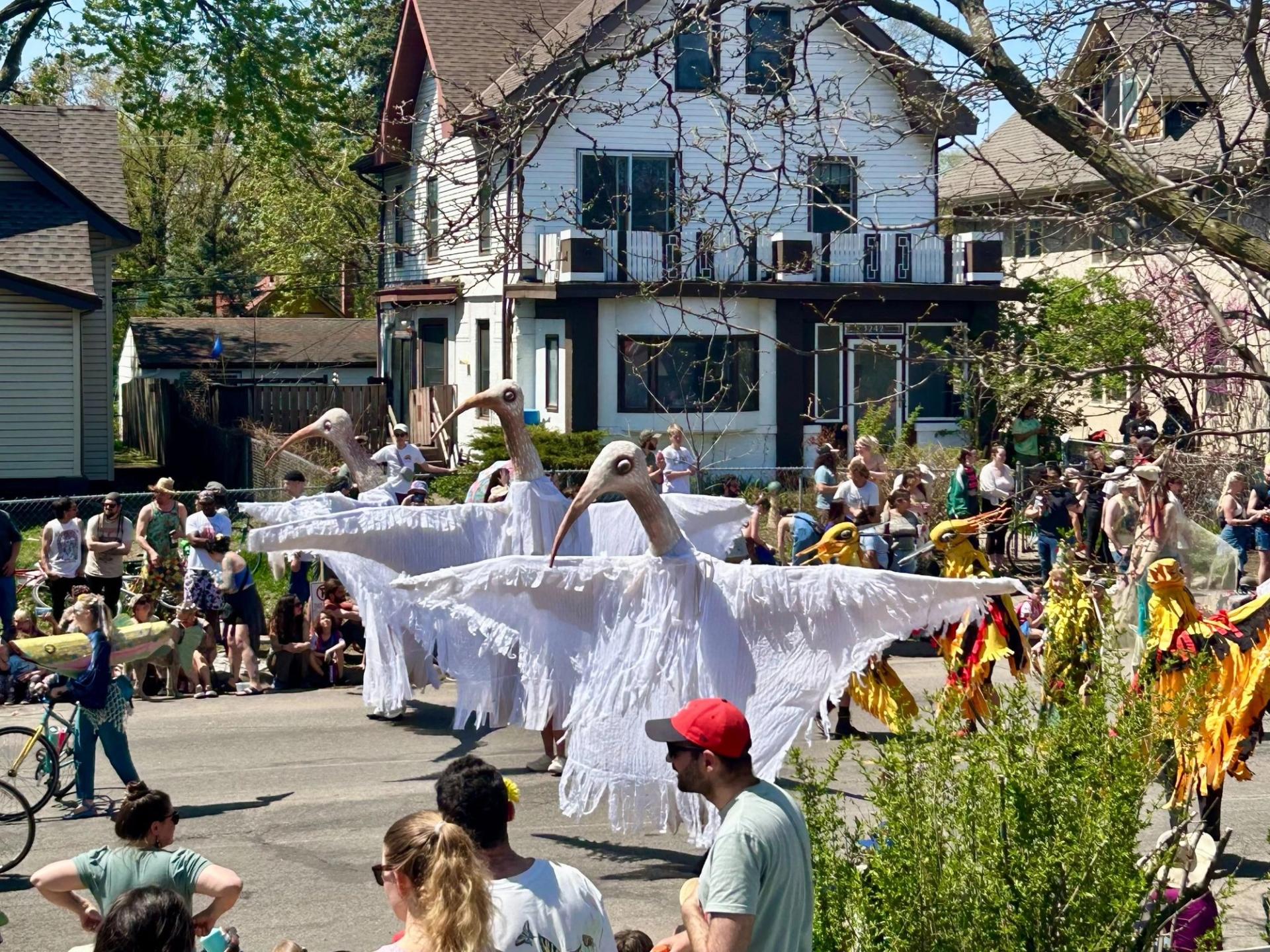A group of people surrounding a float. The float consists of a few large birds