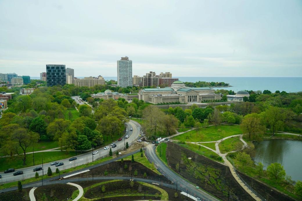 An aerial view of jackson park from the obama presidential center. There are large full trees and roads separating parts of the park