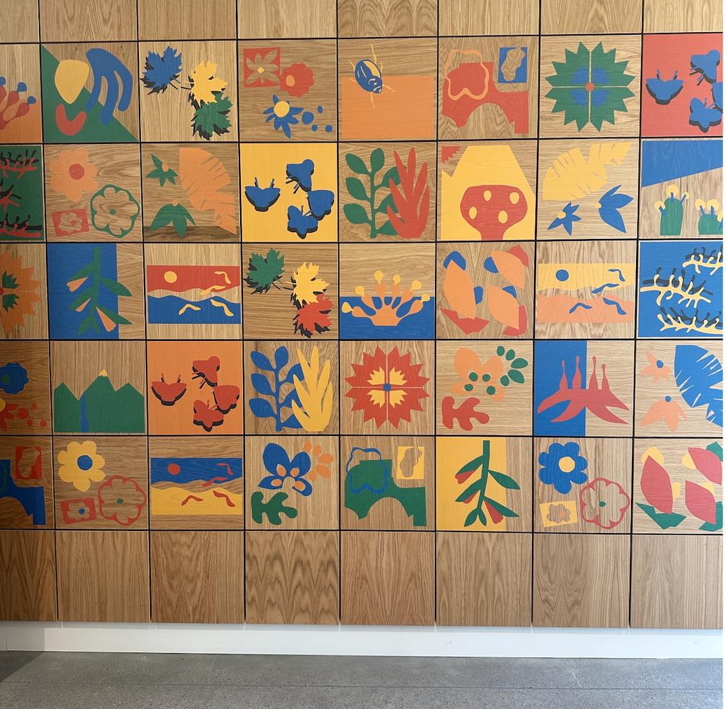 A walk of wooden squares each painted with a design in red, yellow, green, or blue — flowers - leaves, butterflies and more.