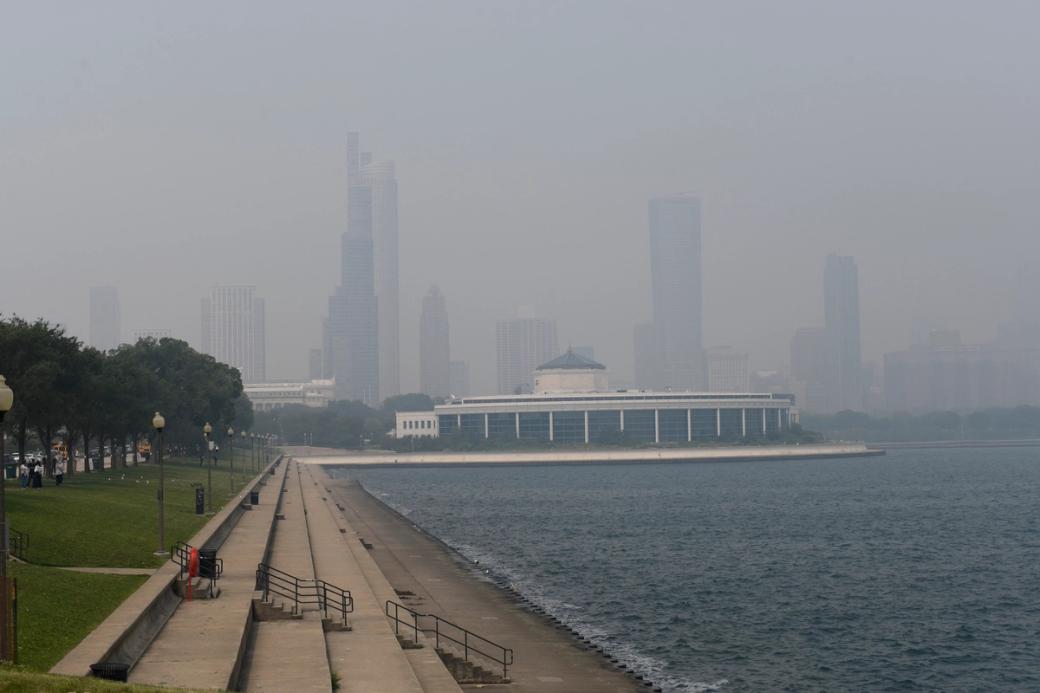 A view by the lake looking at the chicago skyline. A thick layer of smoke has taken over the skyline