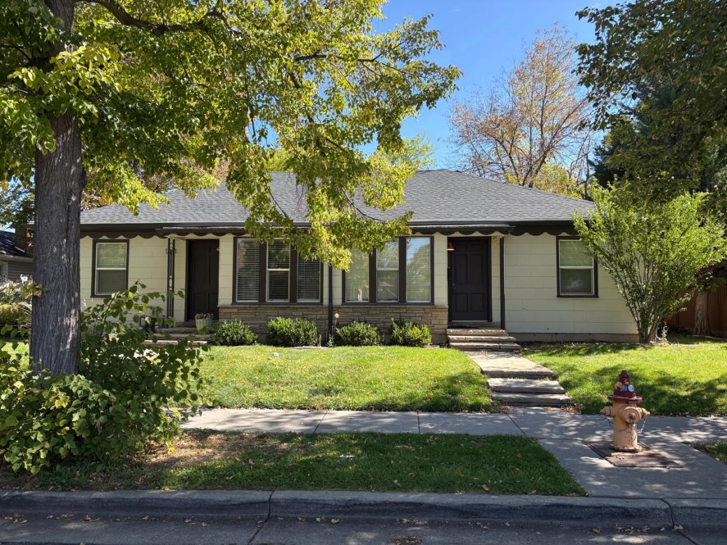 A white and black duplex in Liberty Wells neighborhood that’s surrounded by two trees and a yellow fire hydrant on the right side on a sunny day.