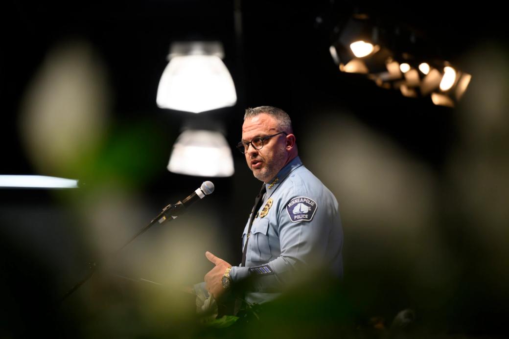 Adult man wearing police uniform stands at podium speaking.