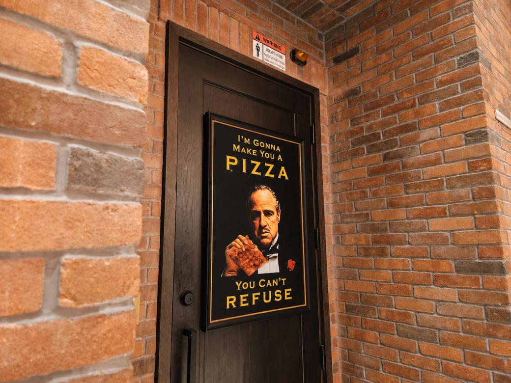 A poster of Marlon Brando on the back of a door that says "I'm Gonna Give you a Pizza You Can't Refuse."