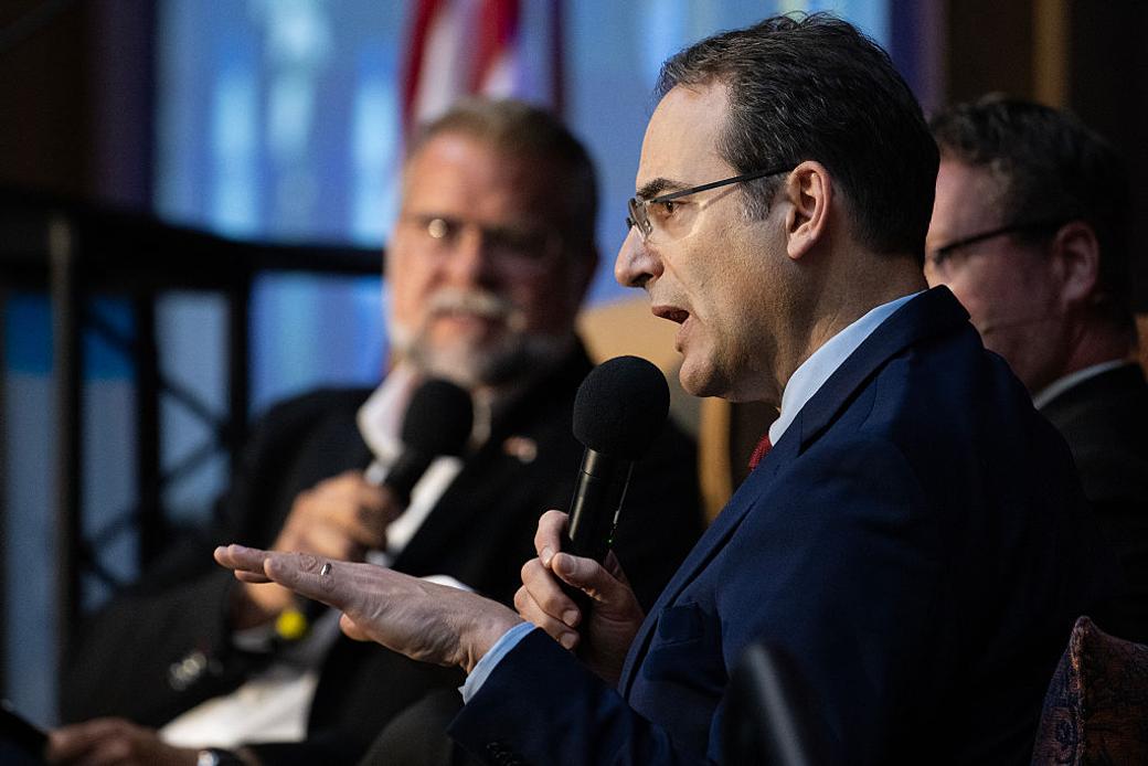 Phil Weiser gestures while speaking at a political forum.