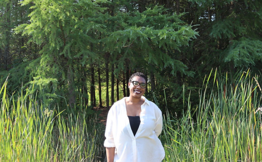 Qwantese Winters stands in a wooded area wearing a white top and smiling