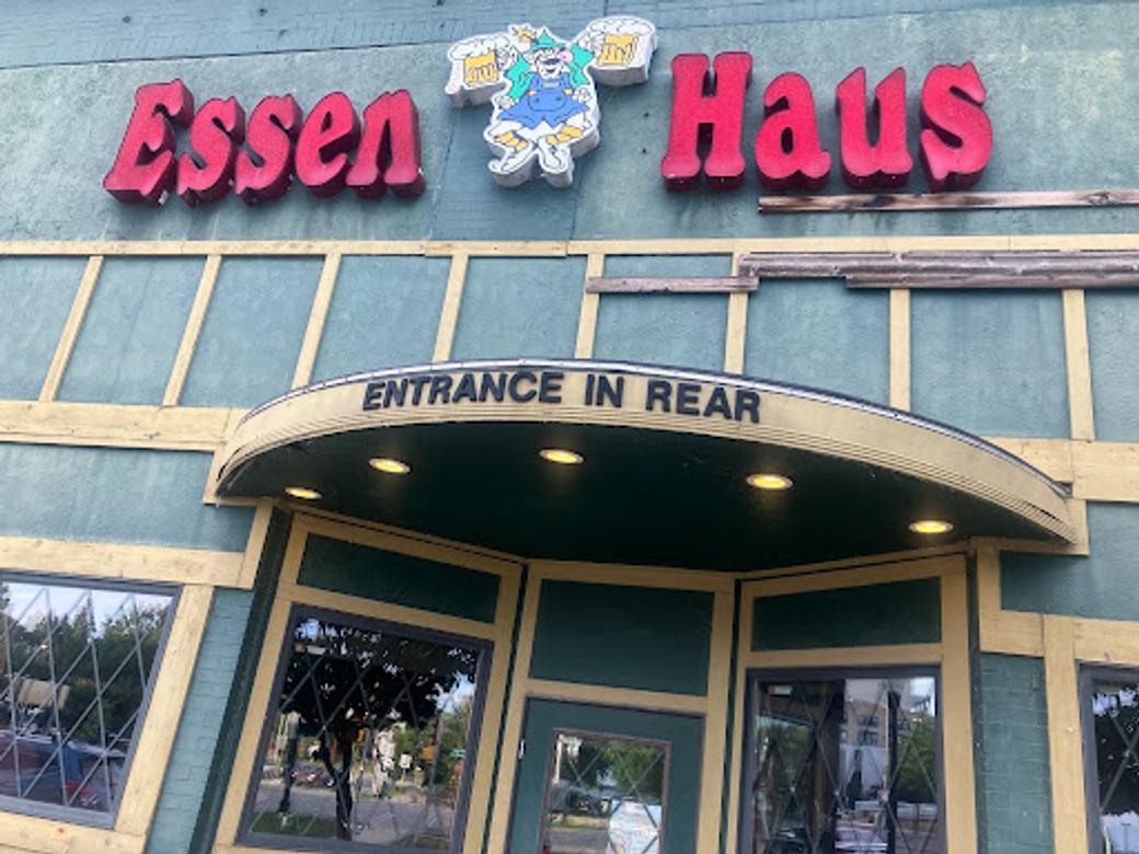 The front of the Essen Haus - a grey building with gold trim and a pink sign.