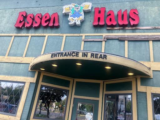 The front of the Essen Haus - a grey building with gold trim and a pink sign.